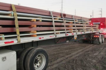 rig and 48 foot long trailer with metal building frames loaded and strapped down