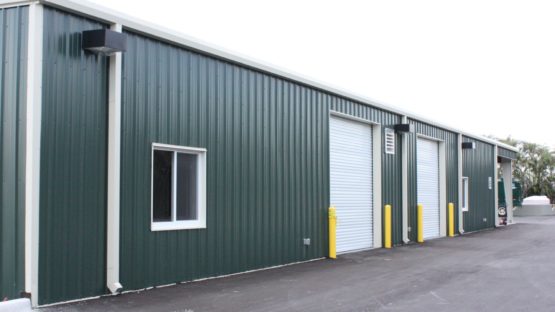 Green golf course maintenance metal building with white trim.